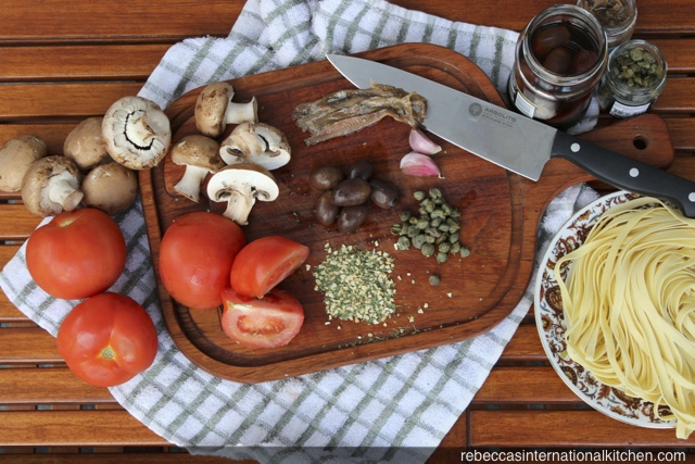Ingredients for Pasta a la Putanesca: tomatoes, capers, olives, anchovies, and mushrooms